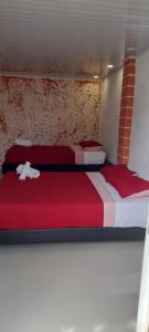圣安德烈斯POSADA HIGH TIDE的配有红色和白色床单的客房内的两张床