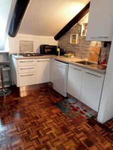 都灵La Mole apartment的厨房铺有木地板,配有白色橱柜。