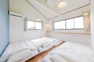 Kōembō三浦海岸 SealightVilla A棟的卧室设有两张床,拥有白色的墙壁和窗户。