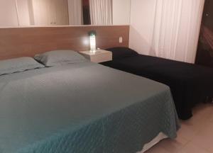 埃斯坦西亚Apartamento na Praia do Saco - Condomínio Villa das Águas的一间卧室配有两张床和一张带台灯的桌子