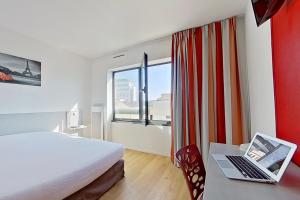 塞纳河畔伊夫里城市艾弗里酒店的酒店客房配有一张床铺和一张书桌上的笔记本电脑