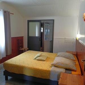 锡拉奥Petite fleur de lentilles的卧室配有一张带黄色床单和枕头的大床。