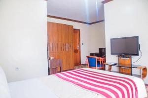 基加利Hotel Karisimbi的一间卧室配有一张床和一台平面电视
