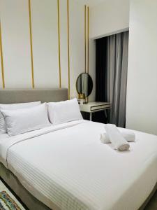 吉隆坡KLCC Suites At Axon Residence的卧室配有带毛巾的大型白色床