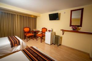 库斯科Hotel Agustos Cusco的酒店客房带一张床、一张桌子和椅子