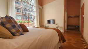 布宜诺斯艾利斯Casa Par Grand Suites的一间卧室设有一张床和一个大窗户