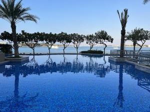 迪拜Lux Living on Palm Jumeirah With Beach Access & Complimentary Golf的一座棕榈树和海洋游泳池