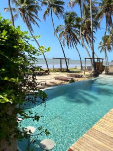 雅帕拉廷加Kuarasy Boutique Hotel Japaratinga的棕榈树海滩旁的游泳池