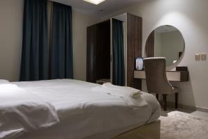 Umm al Khashabأزهار النرجس للشقق الفندقية的一间卧室配有一张床、镜子和椅子