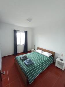 Lajes das FloresOCEANVIEW的一间卧室配有一张带绿色床单的床和一扇窗户。