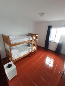 Lajes das FloresOCEANVIEW的客房设有两张双层床,铺有红色瓷砖地板。