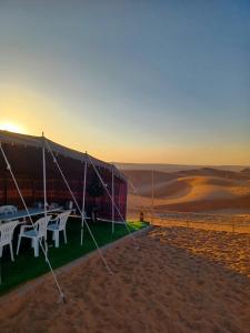 BadīyahSunrise Desert Local Private Camp的沙漠中带桌椅的帐篷