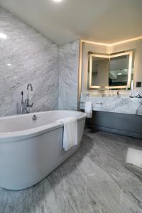 乌鲁阿潘乌鲁阿潘假日酒店的一间带浴缸和大镜子的浴室