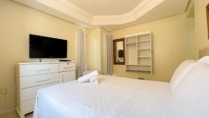 邦比尼亚斯Pousada Azores Bombinhas的卧室配有白色床和平面电视