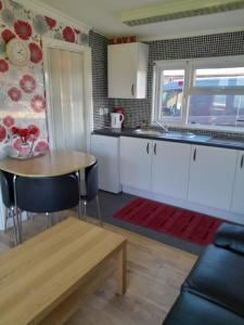 梅布尔索普B8 lovely chalet的厨房配有白色橱柜和木桌