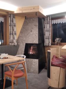 莫尔韦诺Rifugio La Montanara的客厅设有壁炉、桌子和椅子