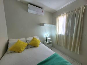 福塔莱萨Teto Hospedagens的一间卧室配有一张带黄色枕头的床和一扇窗户