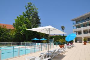 西布勒Appartement Golf et Nivelle avec piscine et parking的一座带椅子和遮阳伞的游泳池位于一座建筑旁边