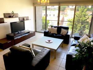 安曼Sleek & Cozy Apartment with Pool & Patio In Abdoun的带沙发、桌子和电视的客厅