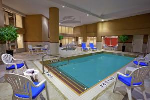 米西索加多伦多机场希尔顿花园酒店的游泳池位于酒店客房内,配有椅子和桌子