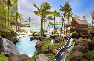 檀香山夏威夷威基基海滩希尔顿度假酒店的一个带瀑布和水滑梯的度假游泳池