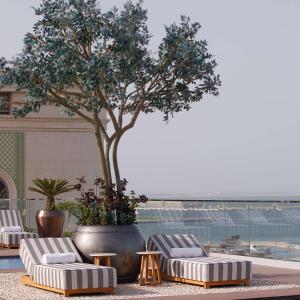 多哈The Plaza Doha, LXR Hotels & Resorts的一组躺椅和一棵树,位于一座建筑中