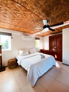 班塔延岛In Dai Aquasports and Beach Resort的卧室配有白色床和木制天花板