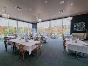 TumbarumbaTumbarumba Motel & Elms Restaurant的用餐室配有桌椅和大窗户