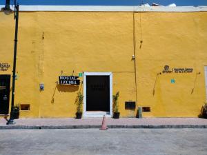 巴利亚多利德Hostal Ixchel - WiFi, Hot Water, AC, in Valladolid Downtown的黄色的建筑,有门和标志