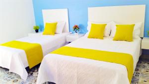 圣玛尔塔Believer Hostel的两张带黄色枕头的床