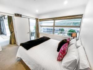 皮克顿Oxley's Waterfront Apartment的卧室配有带枕头的白色床和窗户。