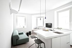 卢布尔雅那艾美一室公寓酒店的白色的厨房配有水槽和椅子