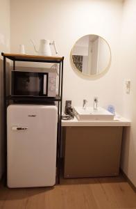 东京MARUKOU HOTEL的水槽旁冰箱上方的微波炉