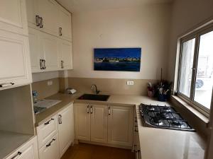 特拉维夫Family Park apartment with 2 bedrooms的厨房配有白色橱柜、水槽和炉灶。