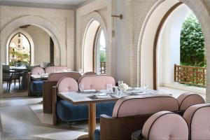 利雅德InterContinental Durrat Al Riyadh Resort & Spa, an IHG Hotel的餐厅设有粉红色的桌椅和拱门