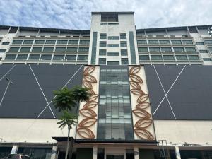 Kota SamarahanSUMMER SUITES APARTMENT-The Summer Shopping Mall的一座高大的建筑,前面有一棵棕榈树