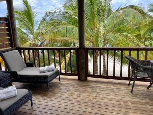 阿罗朗吉Rarotonga Villas Absolute Beachfront的门廊配有椅子和棕榈树,位于酒店后面