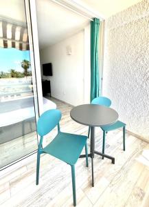 美洲海滩Borinquen Vista Mar的窗户客房内的两张蓝色椅子和一张桌子