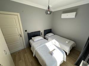 安塔利亚Tas Homes Antalya的配有白色床单的客房内的两张床