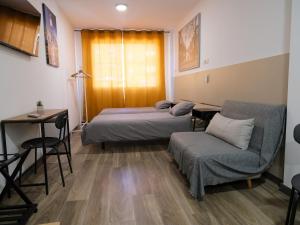 马德里Alianza Suites的一间设有两张床、一张桌子和一把椅子的房间