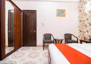 胡志明市Tan Hoang Long Hotel的一间卧室配有一张床、两把椅子和一扇门