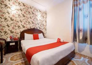 胡志明市Tan Hoang Long Hotel的一间卧室配有红色和白色床单