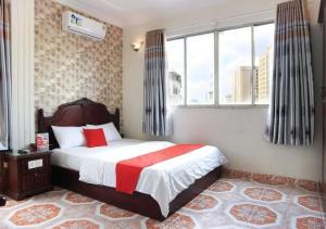 胡志明市Tan Hoang Long Hotel的一间卧室配有一张带红白毯子的床