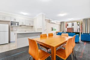 悉尼APX帕拉马塔公寓式酒店的厨房以及带木桌和椅子的用餐室。