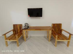 瓜拉丁加奴ASM Roomstay-4-2 Queen Beds的一张木桌,配有两把椅子和墙上的一台电视