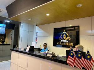 吉隆坡Al Amin Muslim Friendly Hotel的两名坐在酒店大堂柜台的宾客
