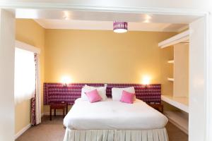 LimuruThayu Farm Hotel的卧室配有带粉红色枕头的大型白色床