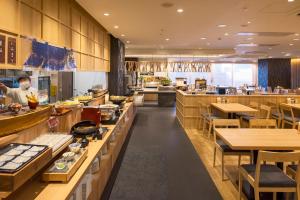 函馆Hotel Global View Hakodate的餐厅设有许多桌子,厨师准备食物