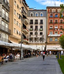 潘普洛纳Premium piso @Plaza del Castillo的一群人沿着街道走着,街道上有许多建筑