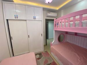 沙姆沙伊赫Sharm Hills Aqua park Resort的卧室配有粉红色的双层床和白色的橱柜。